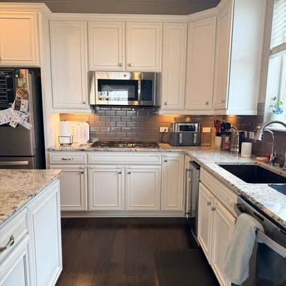 Freshly cleaned white kitchen with clear granite counters and polished appliances